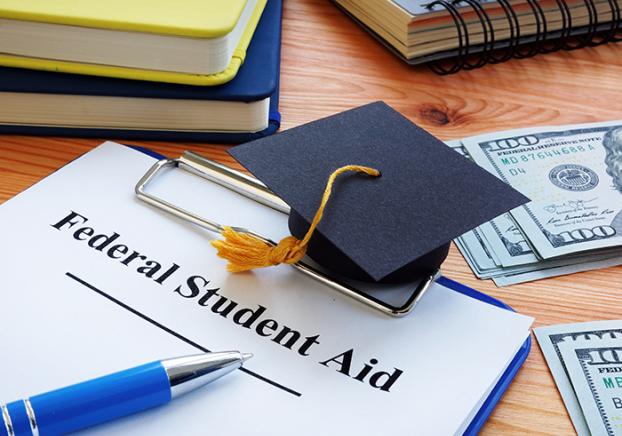 Federal student aid papers and small graduation cap.